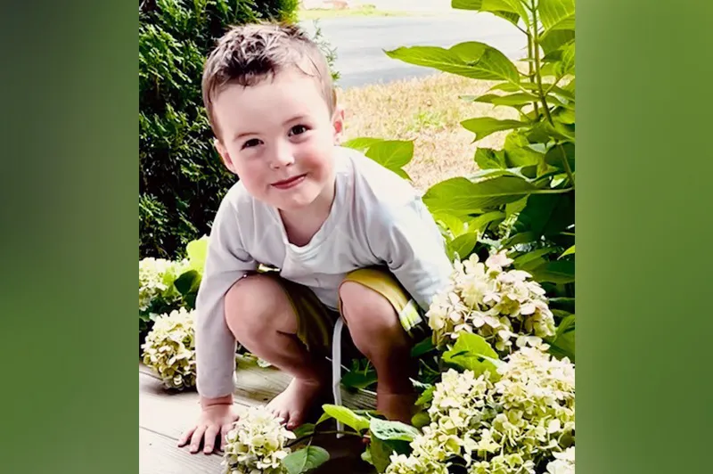 Boy crouches on ground, surrounded by various plants