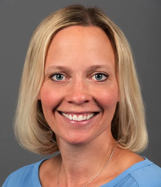 A blonde woman, Lauren McGlynn, smiles at the camera for her headshot.