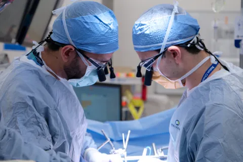 Two clinicians are at work in an operating room