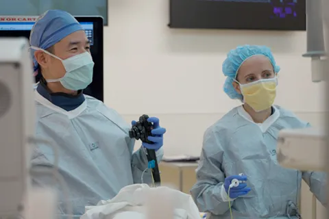 Two clinicians in scrubs look away from camera