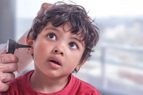 Clinician uses otoscope to examine boy's right ear